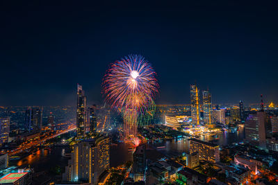 Firework display over city lit up at night. high angle view of illuminated buildings 