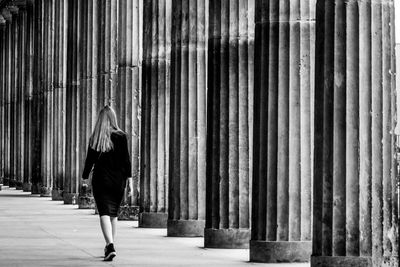 Rear view of woman walking by columns in corridor