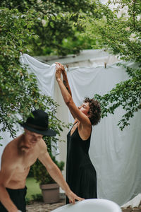 Young couple holding hands while standing against trees