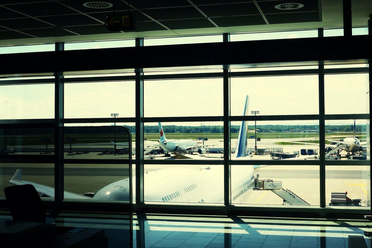 window, glass - material, indoors, transparent, built structure, architecture, glass, sky, airport, city, day, chair, restaurant, looking through window, table, reflection, modern, men, building exterior