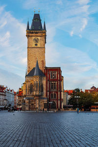 Clock tower and old prague city hall buildings view from below agains morning sky and no people