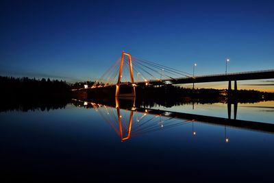 Illuminated bridge over lake against clear blue sky