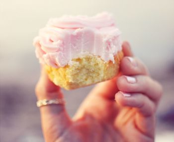 Close-up of person hand holding pastry with bite taken out