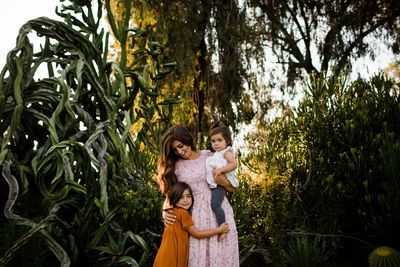 Wide shot of mother & two daughters in desert garden in san diego