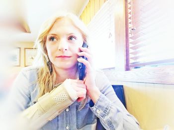 Woman talking on phone while sitting at restaurant