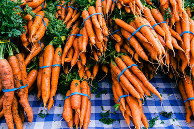 Farm fresh produce on tabletop at local farmer's market orange carrots in bundles with blue bands