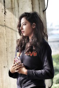 Portrait of beautiful woman standing against wall