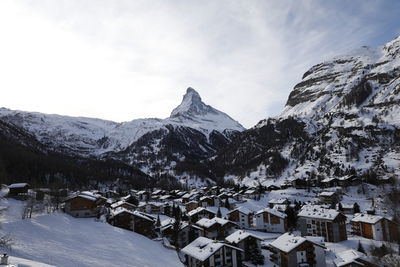 Houses on snowcapped mountain against sky