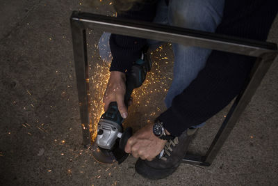 Man sawing steel frame with sparks flying