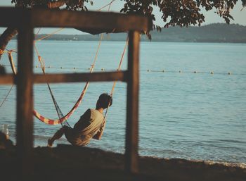 Man on hammock at beach against sky