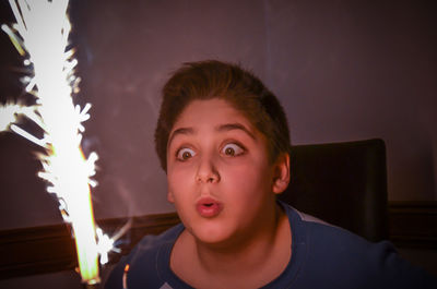 Cute boy blowing sparkler at home