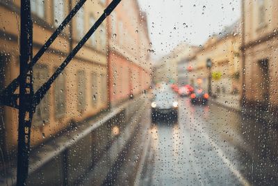 Car on street seen through wet glass window