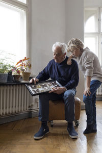 Grandfather showing butterfly collection to grandson at home