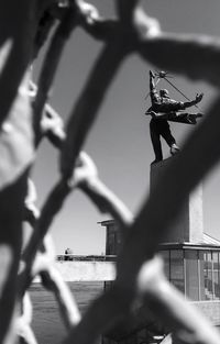 People on metal fence against sky in city
