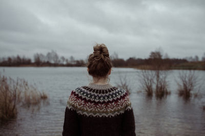 Rear view of woman standing at lake against sky