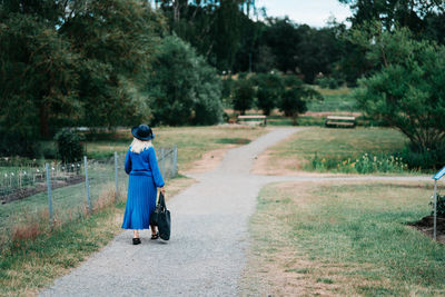 Rear view of woman walking on road amidst trees