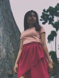 Low angle view of woman standing by tree