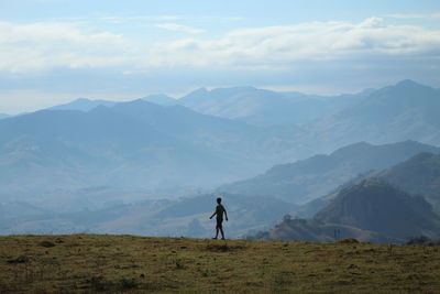 Rear view of man walking on mountain against sky