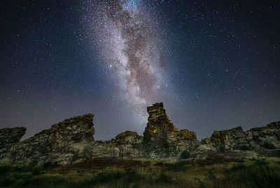 Low angle view of rock formation against sky at night