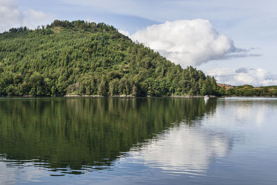 Scenic view of lake by trees against sky