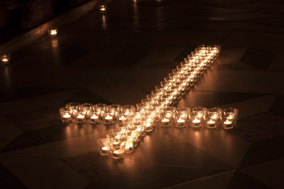 High angle view of tea light candles in cross shape on floor in church