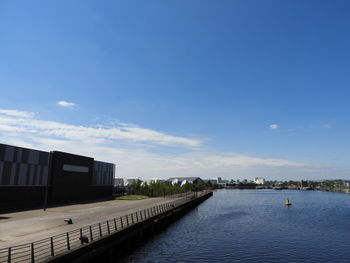 Scenic view of river by buildings against blue sky
