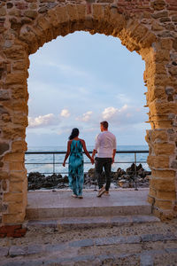 Rear view of couple with umbrella against sky