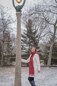 Smiling woman standing on snowy field during snowfall