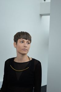 Young woman looking away while standing against wall