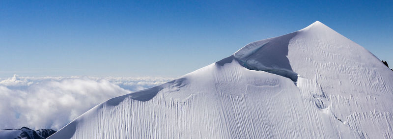 Scenic view of snow covered mountain against blue sky