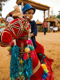 Girl looking away while sitting on artificial decorated horse