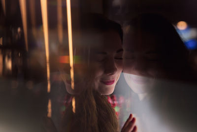 Close-up of woman standing by glass in darkroom