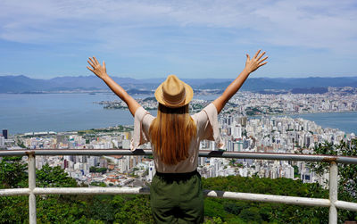 Tourist woman with raising arms from belvedere in florianopolis city, santa catarina, brazil.