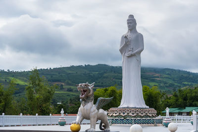 Statue by sea against sky