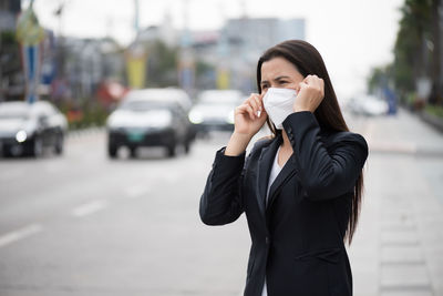 Businesswoman wearing mask standing on road