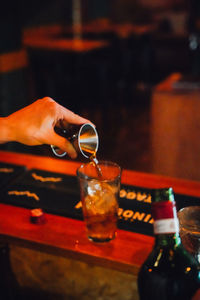 Midsection of man holding beer glass on table