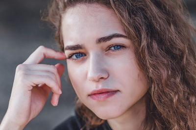 Attractive face of young woman with wavy hair. blue eyes, black eyebrows, smile.