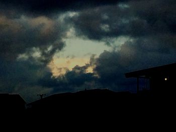 Low angle view of silhouette house against sky