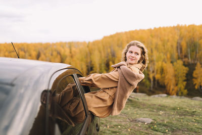 A pretty girl enjoys solitude drinks coffee walks in the autumn forest in nature in fall