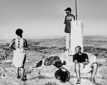 Friends standing on beach against clear sky