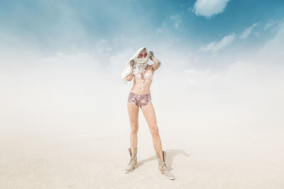 Full length of woman standing on beach against sky