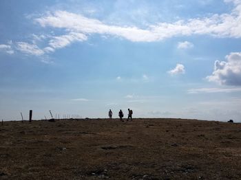 People walking on landscape against sky