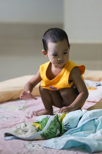 Cute boy sitting on bed at home