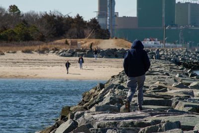 Back of boy walking along rock path in ocean