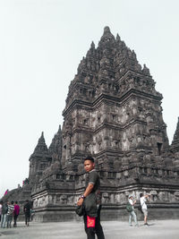 People at temple outside building against sky