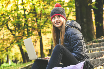 Girl sitting in the park using laptop. teen using computer, chat with friends and classmates