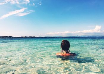 Rear view of woman in sea against sky