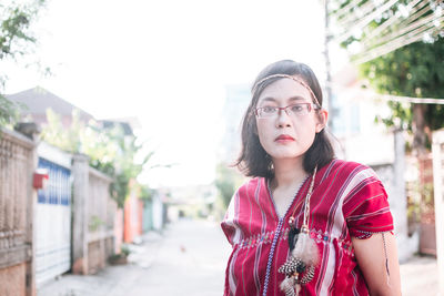 Portrait of young woman standing against buildings