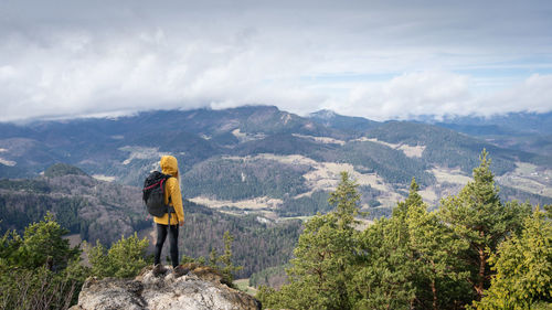Rear view of man standing on mountain against sky