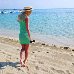 Full length rear view of young woman standing on beach